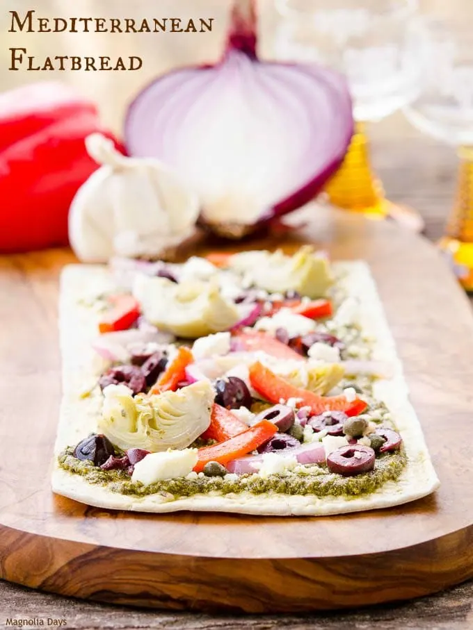 Mediterranean Flatbread is an easy to make meal or appetizer. It's loaded with pesto, artichokes, bell pepper, onion, olives and feta cheese.