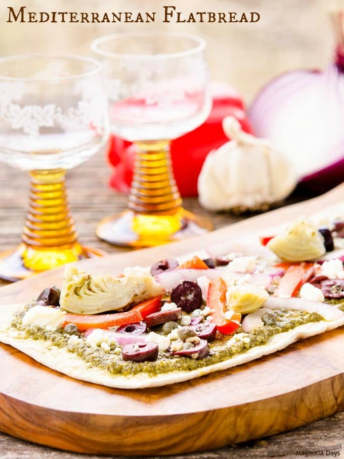 Mediterranean Flatbread is an easy to make meal or appetizer. It's loaded with pesto, artichokes, bell pepper, onion, olives and feta cheese.