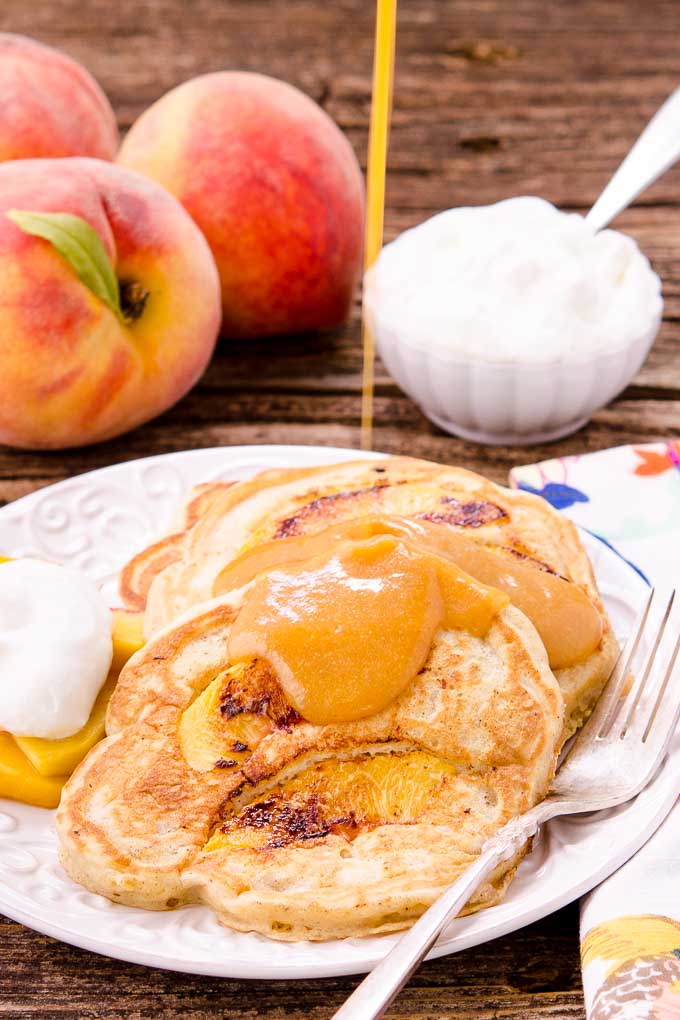 Peach Pancakes with Peach Maple Syrup are made with fresh peaches and a hint of spice. It's a delightful breakfast with summer fruit inside and out.