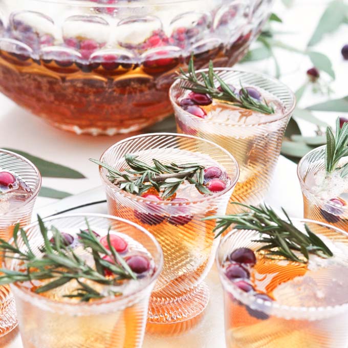 Clear punch glasses and bowl with green garnish and berries