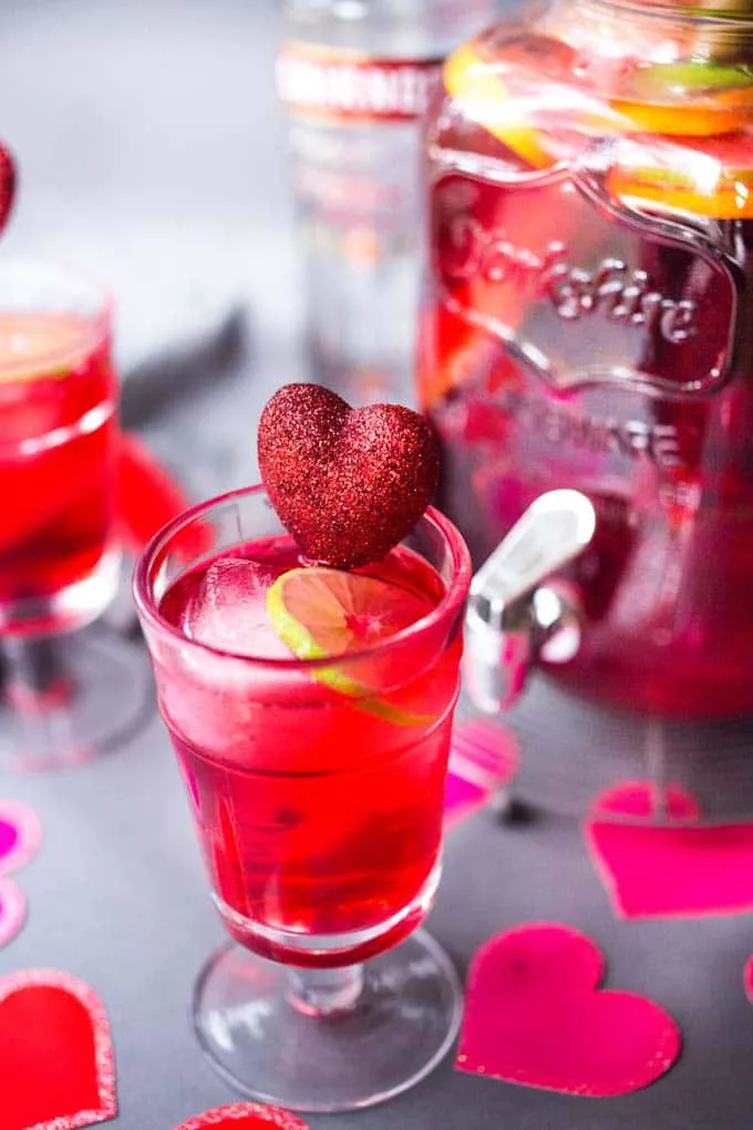 Clear glass of hibiscus punch with heart swizzle stick
