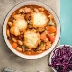 Bowl of pork belly casserole with dumplings and red cabbage with silverware