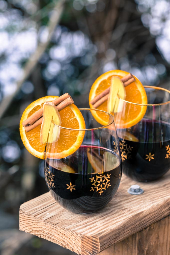 Two glasses of mulled wine with orange slices, ginger, and cinnamon
