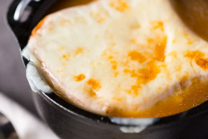 Closeup of melted cheese on a large soup crouton made from toast