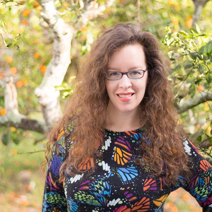 A portrait of Katie Moseman standing in front of citrus trees