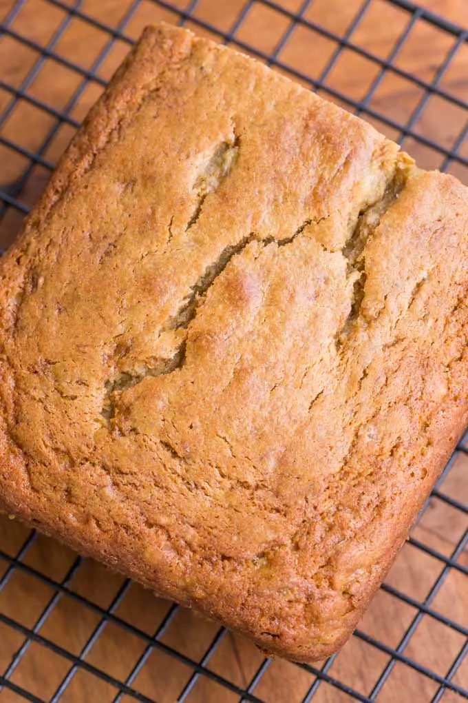 Overhead view of loaf of sorghum banana bread on a black wire cooling rack