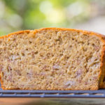 Interior of a loaf of sorghum flour banana bread resting on a rack with green background
