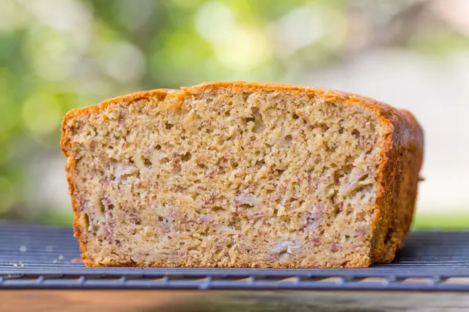 Interior of a loaf of sorghum flour banana bread resting on a rack with green background