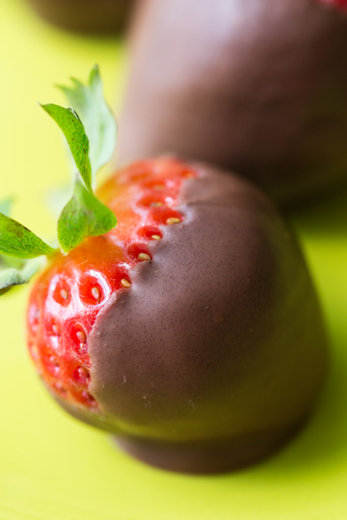 Closeup of a chocolate dipped strawberry on a green plate