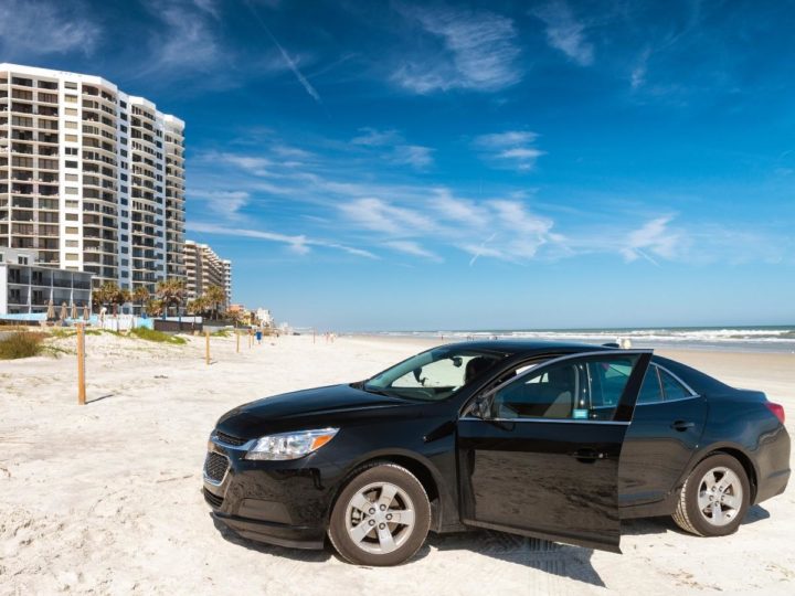 Car on Daytona Beach with condo building in the background